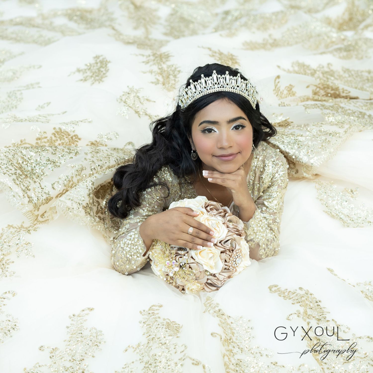 An elegant formal portrait featuring a sparkly crown and champagne-colored dress with ornate beading details.
