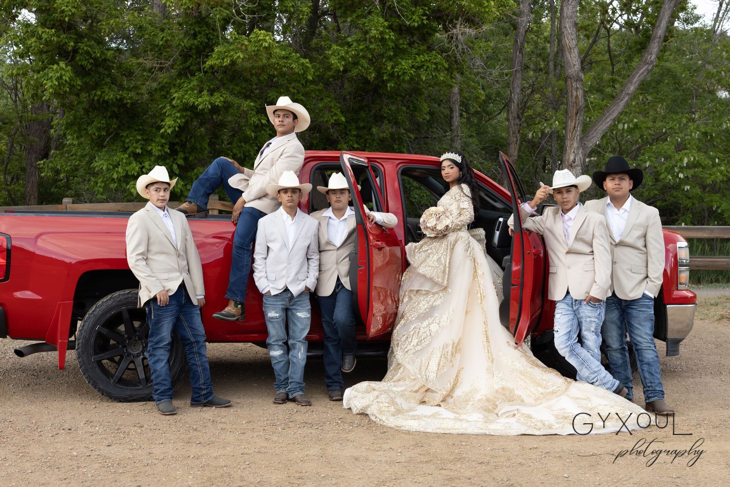 A formal group photo with groomsmen in cowboy hats and boots next to a red pickup truck.
