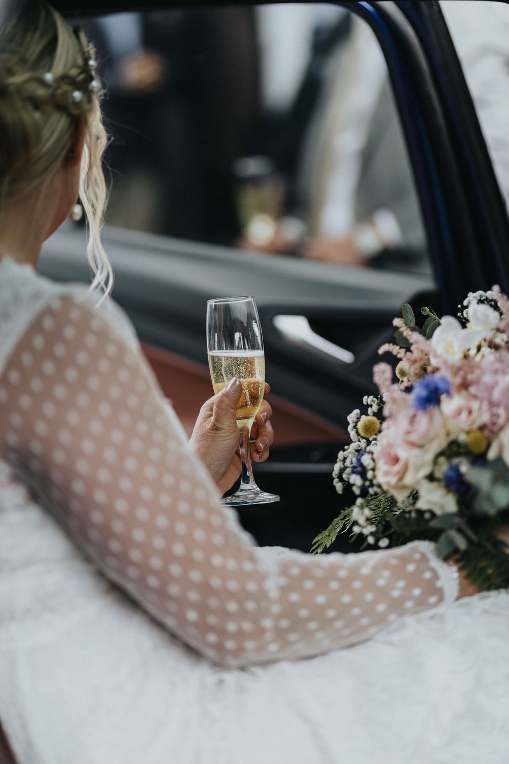 Diana sidder i bilen med en glas champagne¨