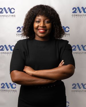 Corporate portrait against backdrop with 2MC Consulting logo wearing black outfit.