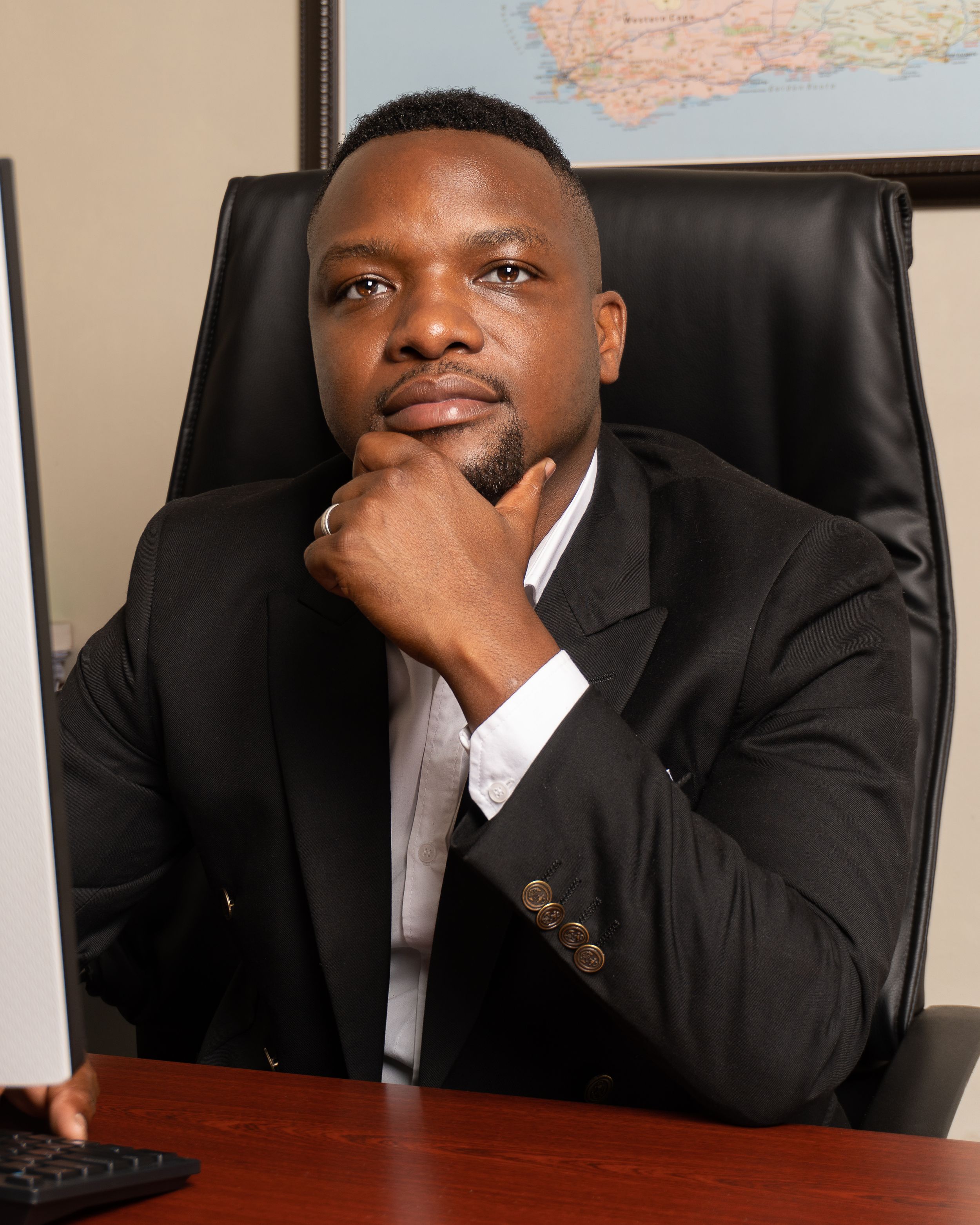Professional portrait in an office setting with a map visible in the background.