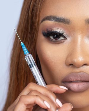 Close-up beauty shot showing eye makeup and holding medical syringe.