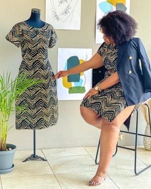 A zigzag patterned dress displayed on a mannequin next to abstract wall art and plants.