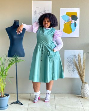 A mint green dress with puff sleeves styled with white socks and colorful footwear against wall art.