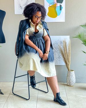 A casual denim dress look styled with combat boots and artistic wall decor in the background.