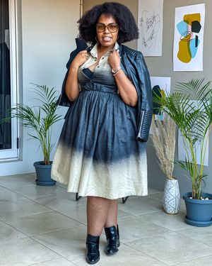 A denim ombre dress paired with a leather jacket and boots in a studio setting.