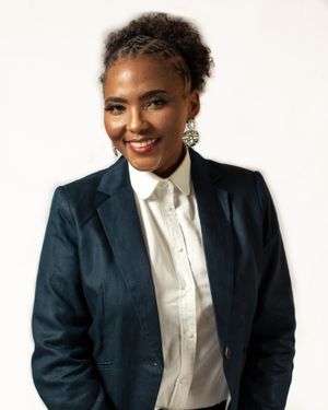 Studio portrait in navy blazer and white shirt with decorative earrings.