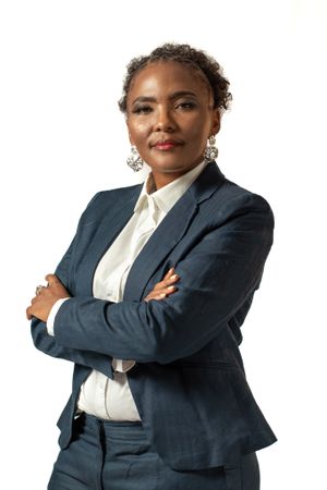 Confident pose in tailored navy suit and white shirt with statement jewelry.