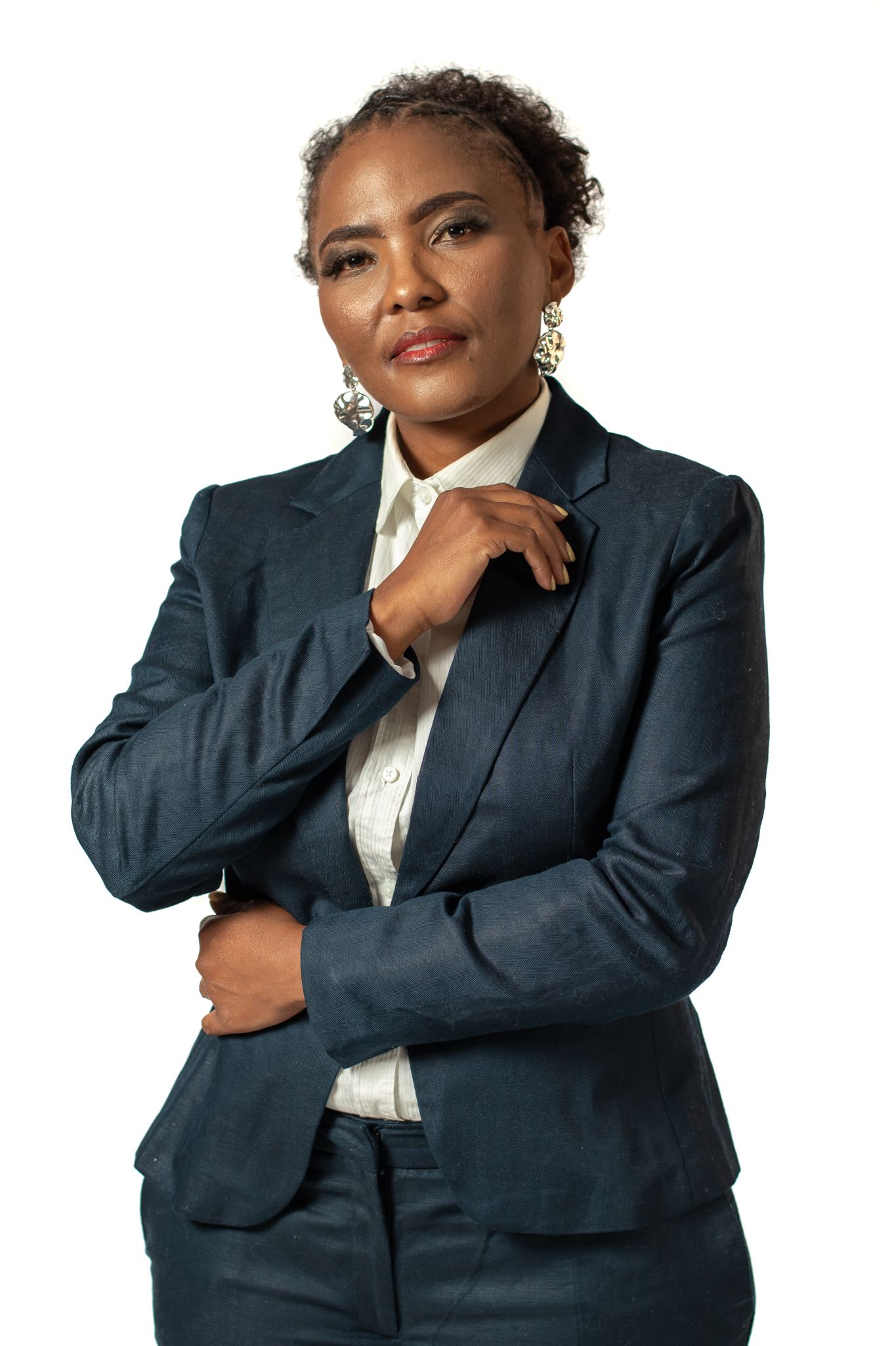 Confident business pose in navy suit with white blouse against studio backdrop.