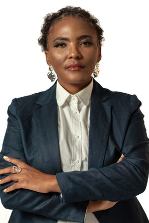 Professional headshot in dark blazer and white button-up shirt with statement earrings.