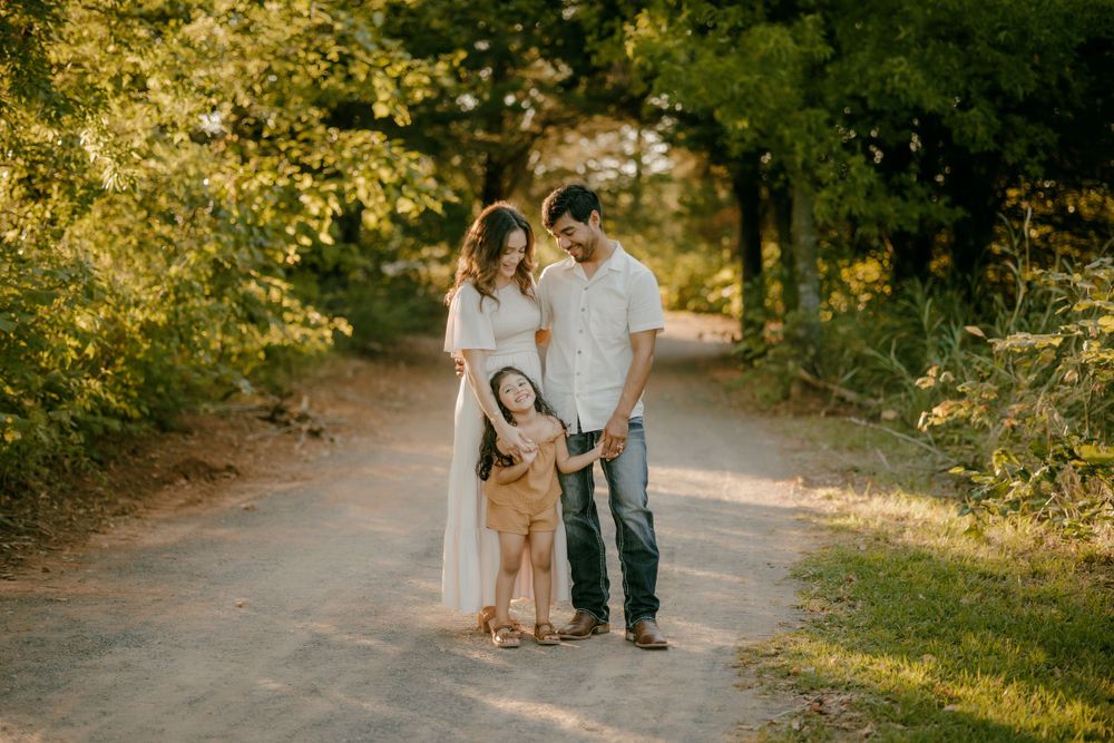 Family standing together on sunlit forest path.