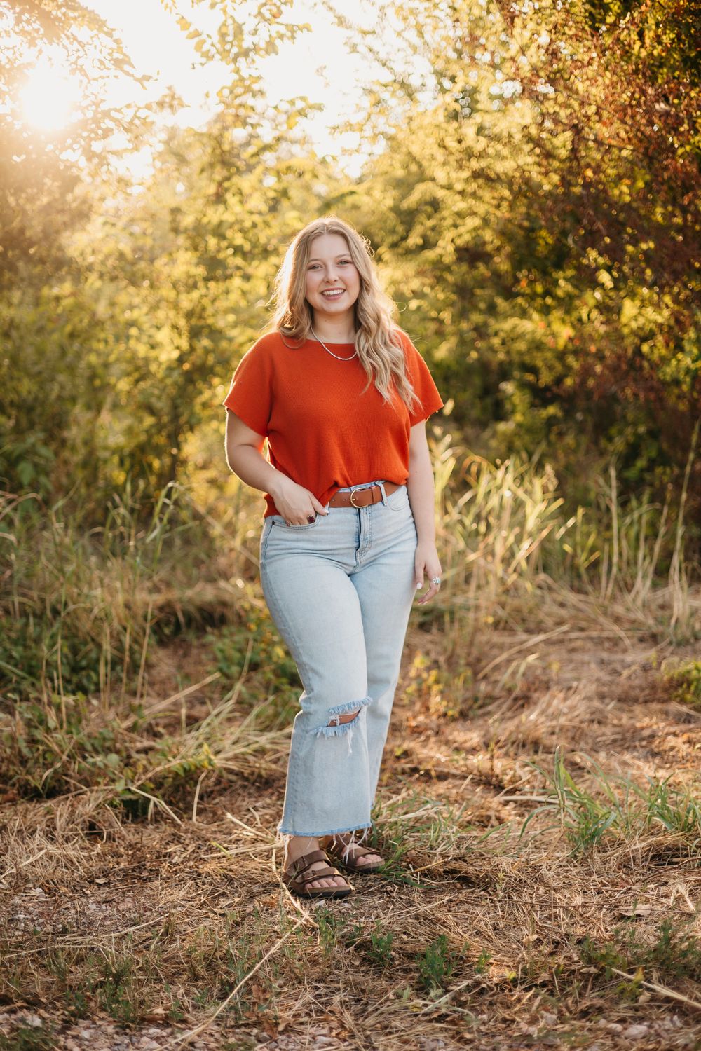 Golden hour outdoor photoshoot featuring casual style with red top and jeans.
