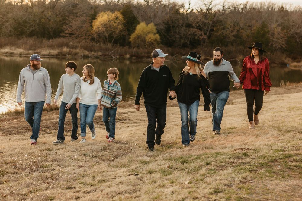 Group walking together on a grassy path near a lake during sunset.