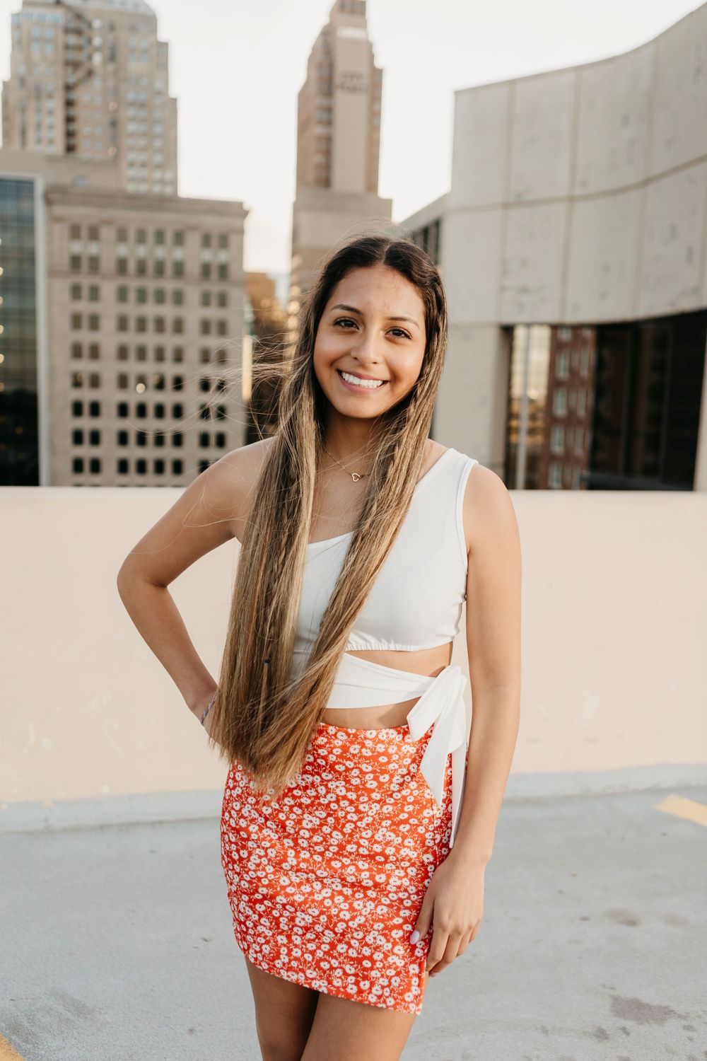 Summer fashion portrait on city rooftop wearing white crop top and floral skirt.