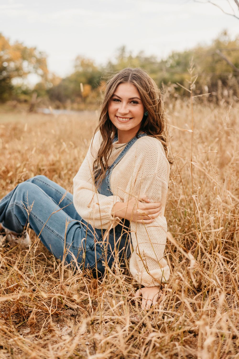 Candid outdoor portraits in a golden wheat field wearing casual sweater and jeans.