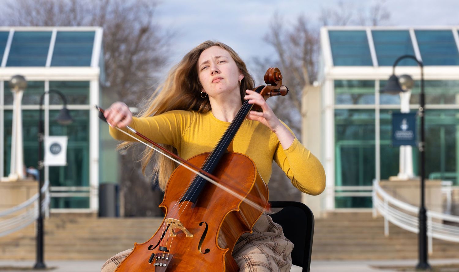 A woman plays the cello while outside.