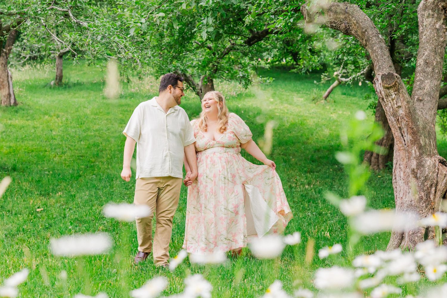 A couple enjoys a romantic moment together in a lush spring garden with white flowers falling around them.