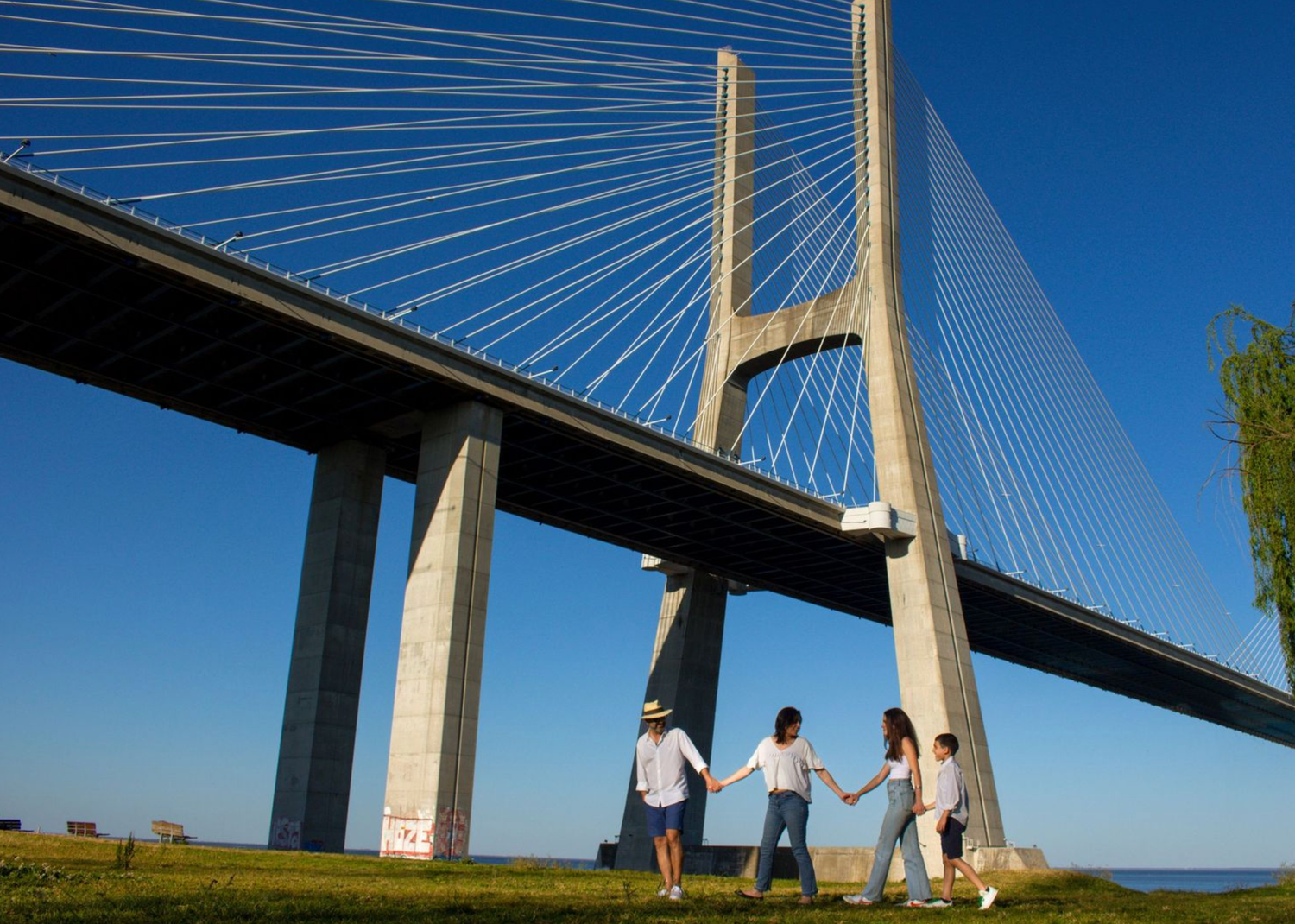 Panoramic view of a modern cable-stayed bridge with white supports against bright blue sky.