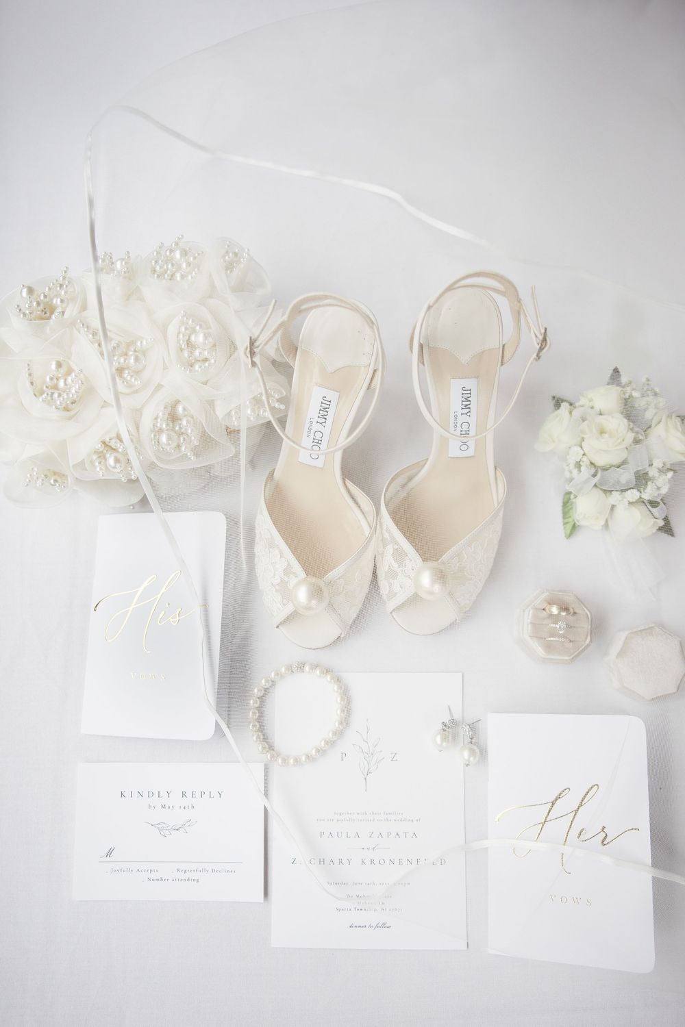 Wedding styling flatlay with white stationery, pearl accessories, and delicate shoes arranged on light background. NJ wedding photographer