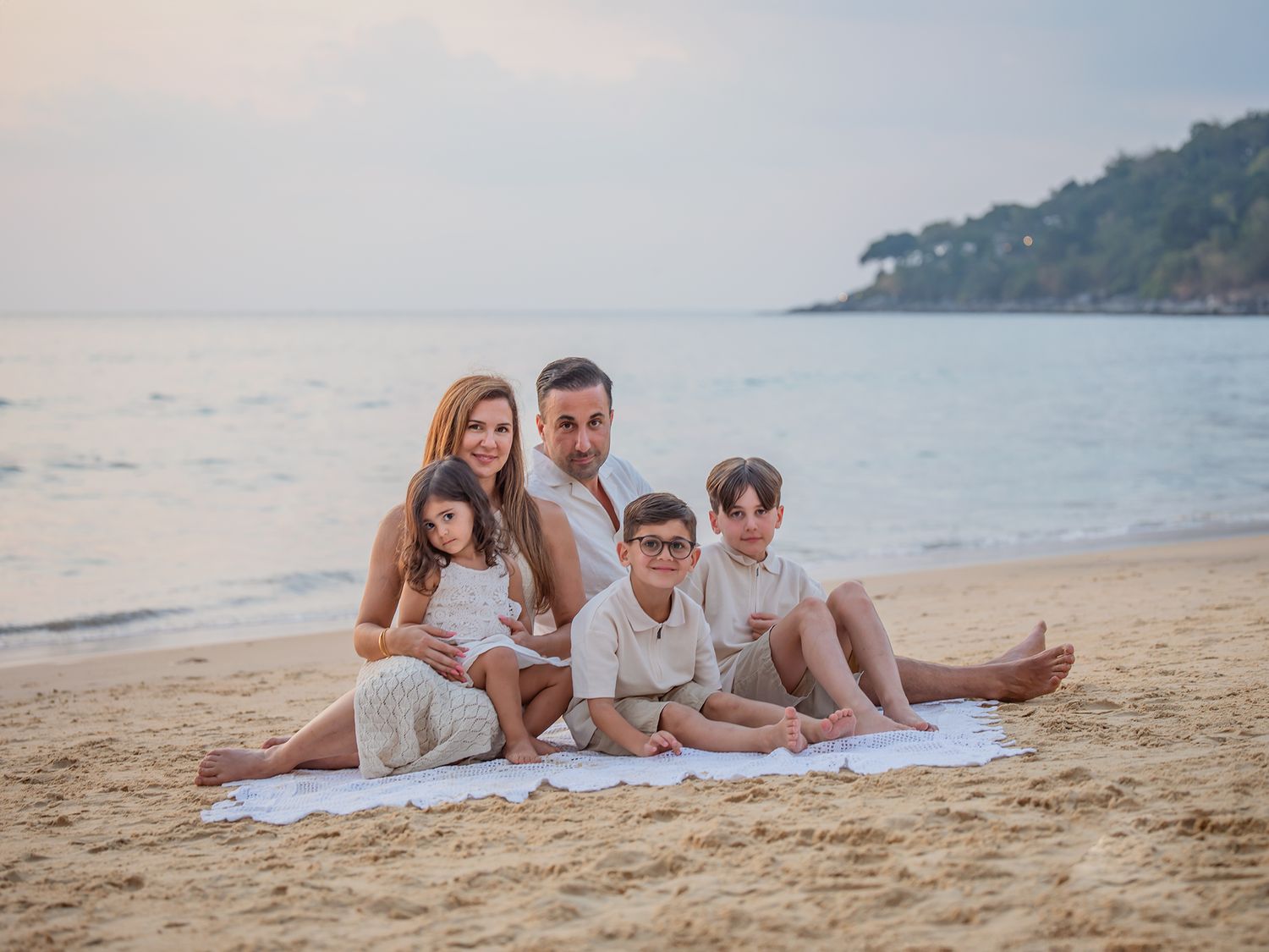 Familj sitter på stranden i solnedgång, Familjefotografering Västerås, MemoriebyM