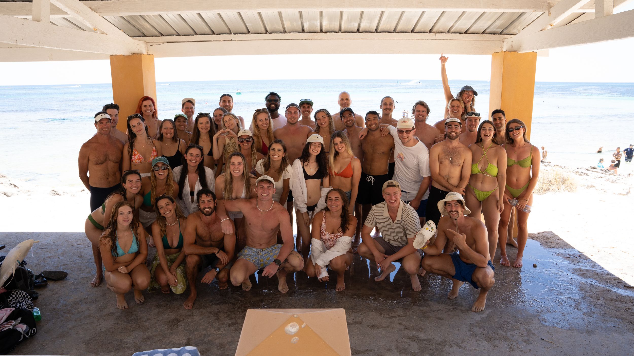 Large group photo session in a covered outdoor space by the ocean.