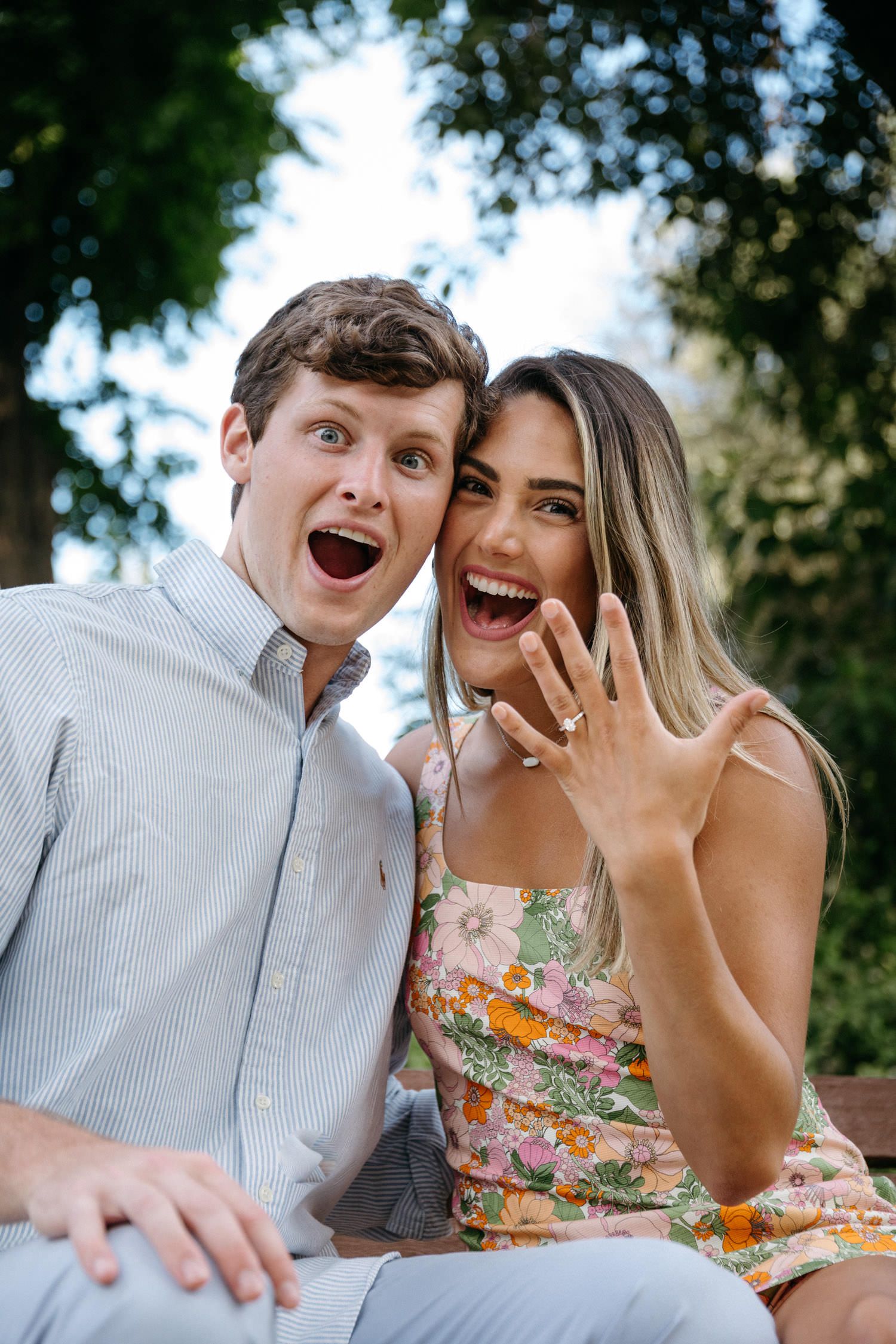 Joyful engagement announcement captured in outdoor garden setting.