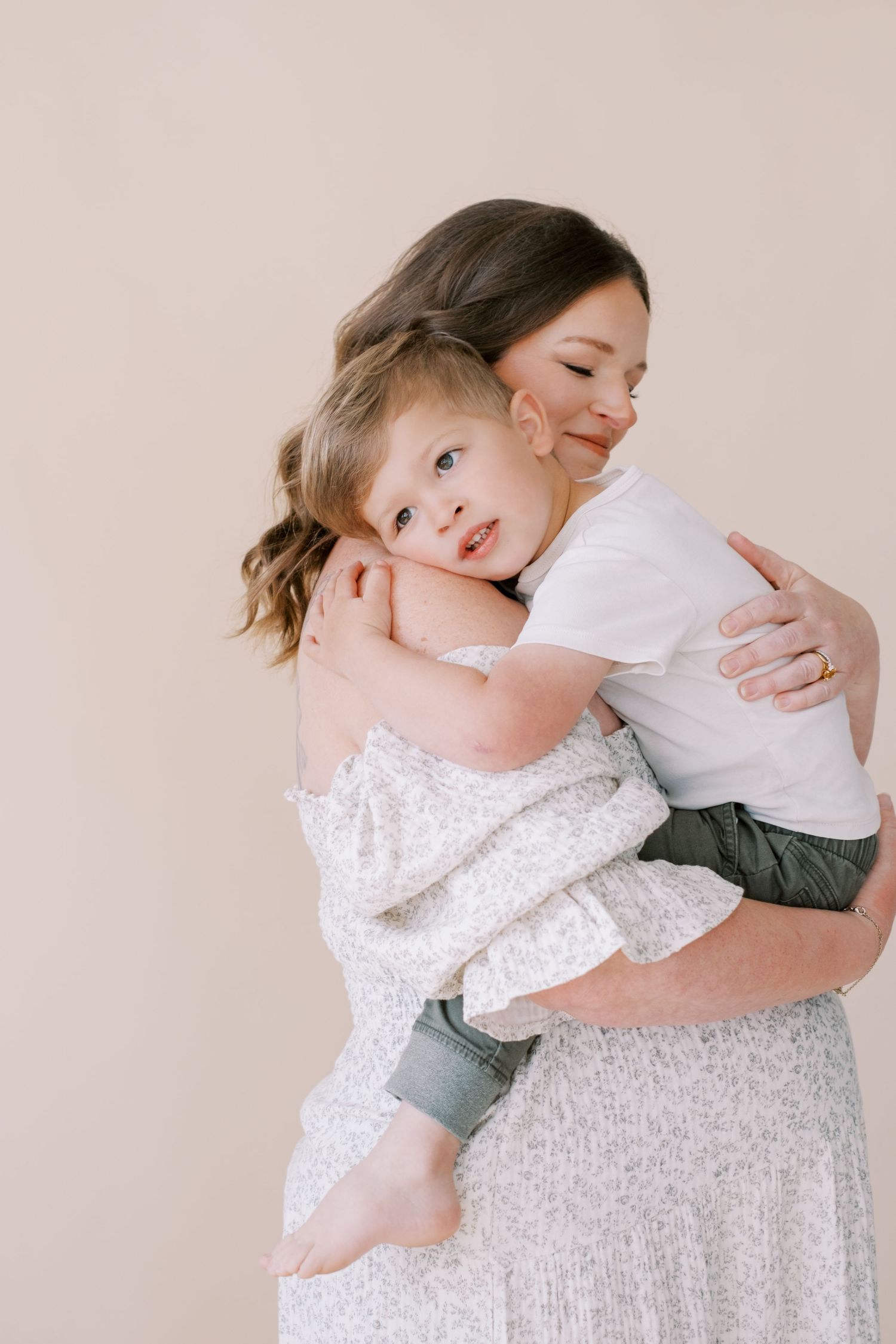 Family coordinated outfits in cream and sage green featuring dresses, pants, shirts, shoes and accessories laid flat.