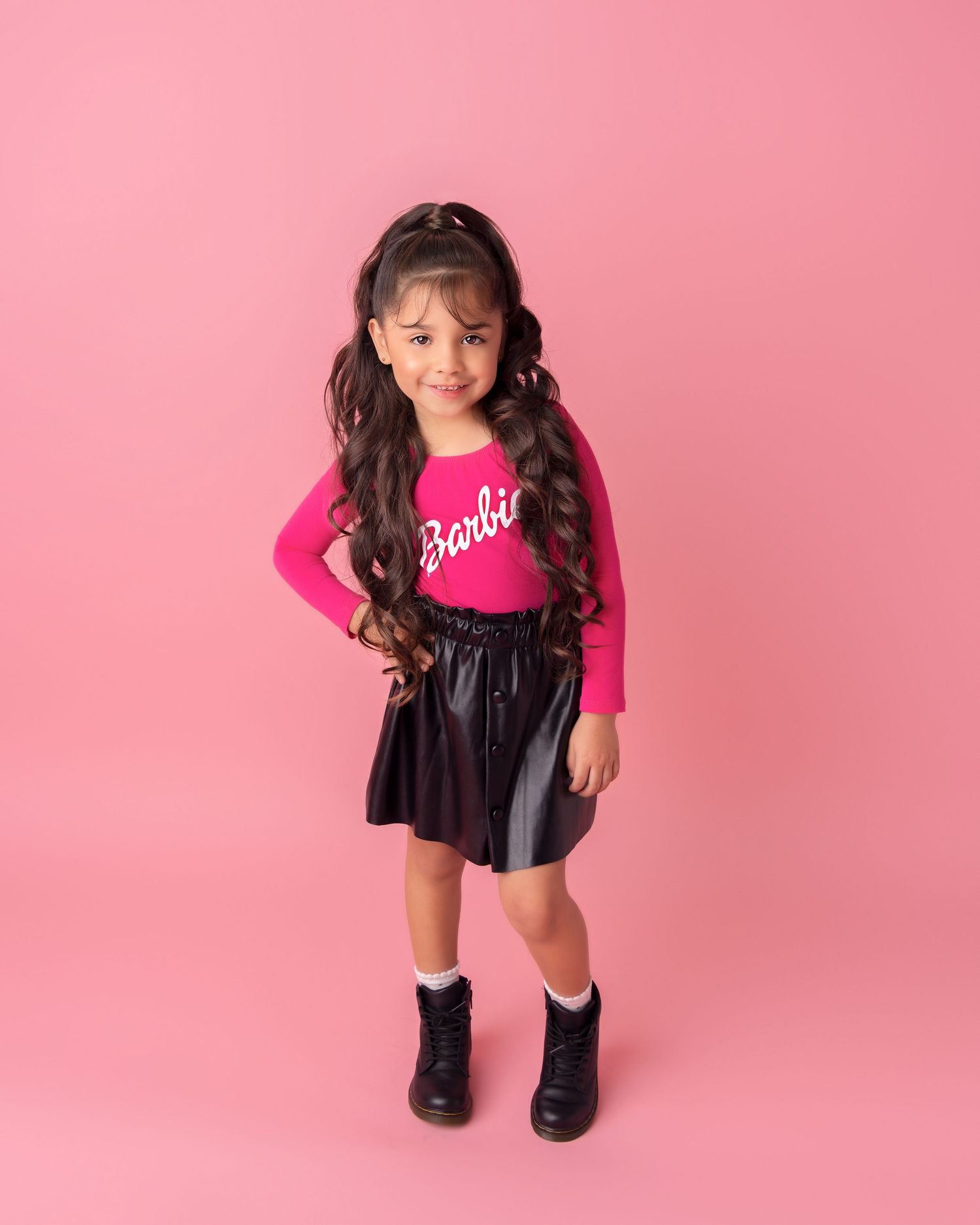 Studio portrait against pink backdrop featuring bright pink outfit.