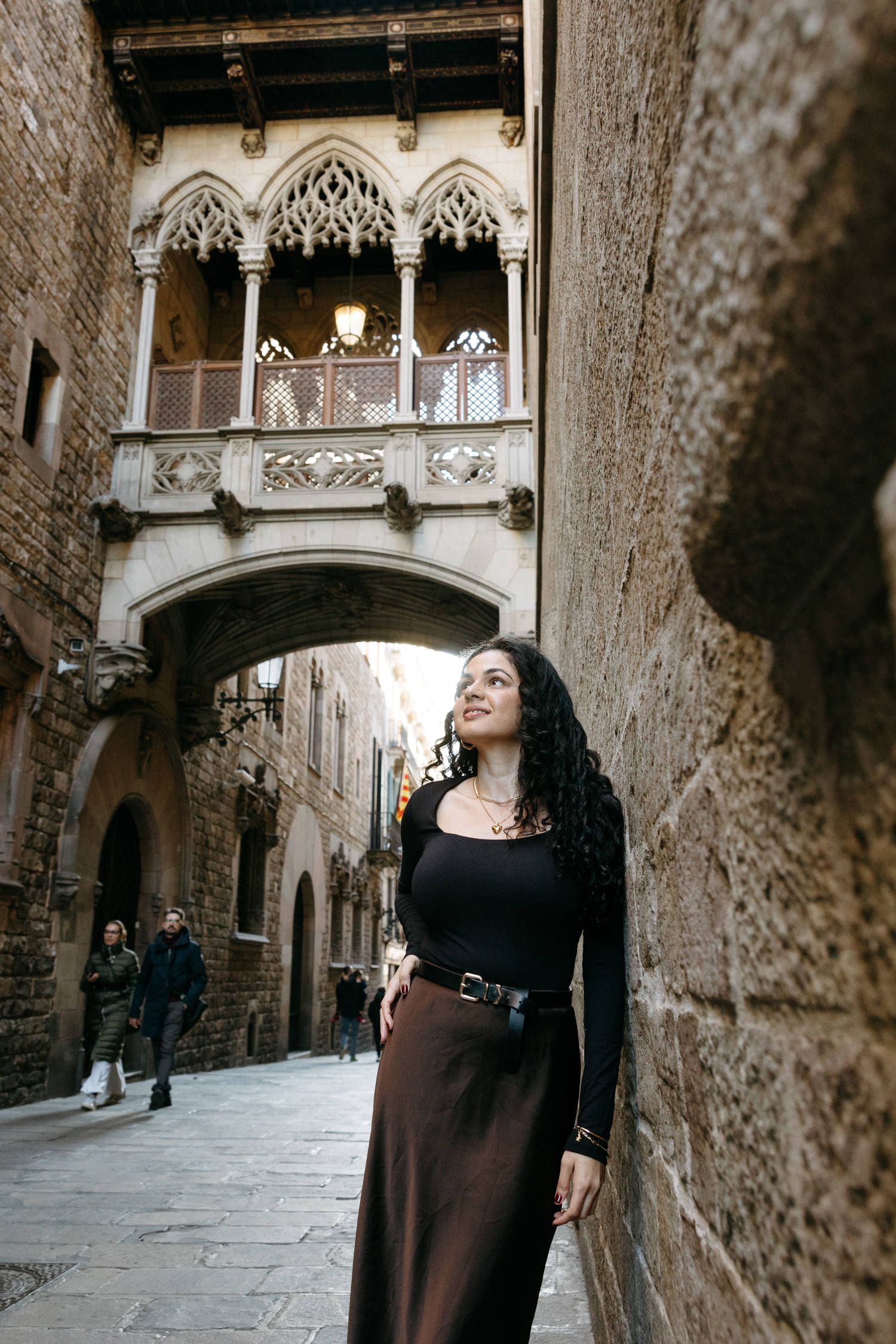 Gothic stone corridor with arched ceilings and decorative medieval architecture in warm lighting.