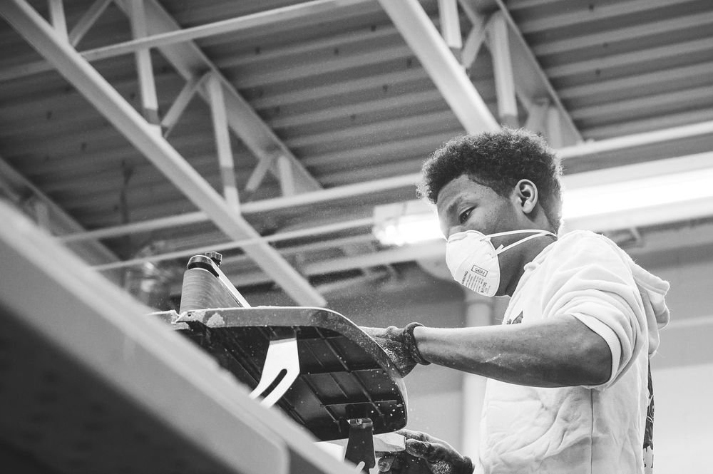 A worker wearing a protective face mask operates an industrial machine in a factory setting.