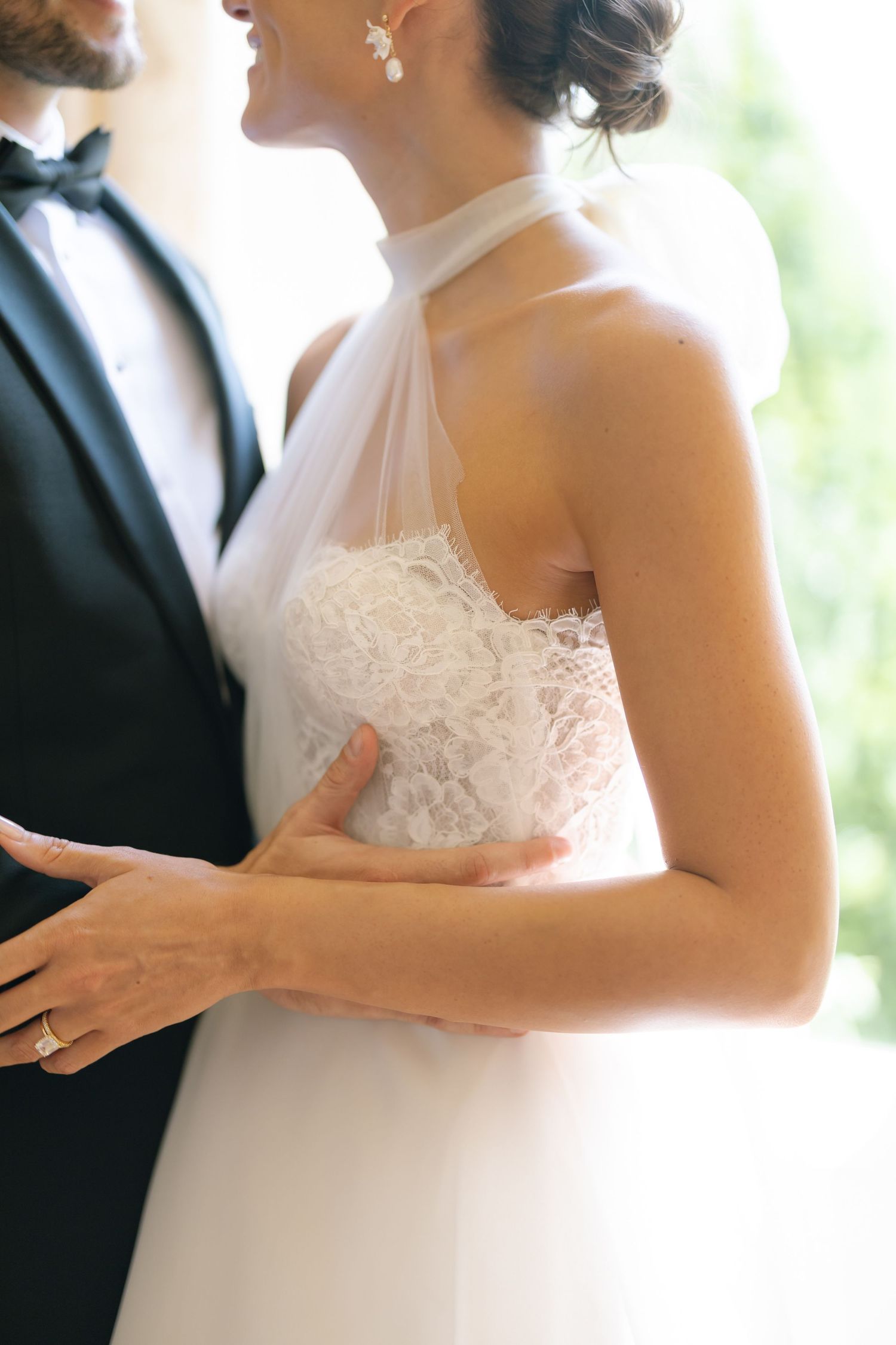Close-up details of a white lace bodice wedding dress in natural lighting.