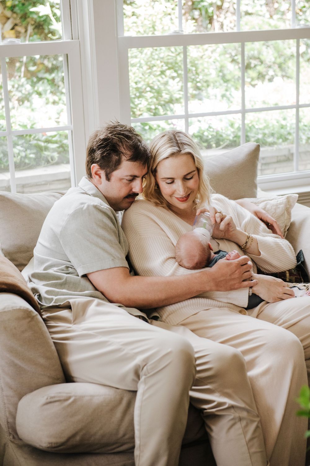 Couple relaxing together on a comfortable white couch in a sun-filled living room.
