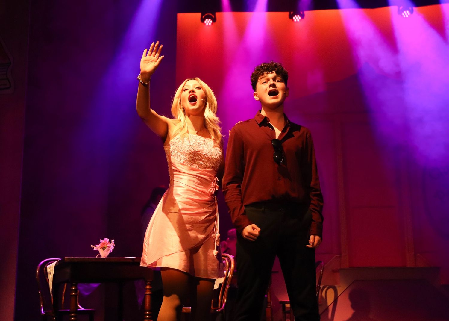 Performers on stage performing during concert with dramatic purple and red stage lighting effects.