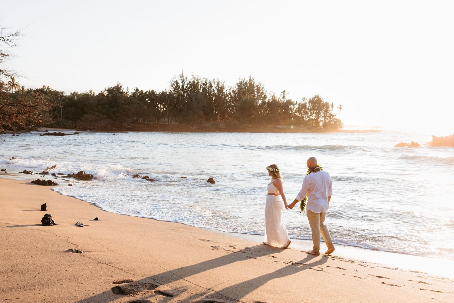 A romantic beachside ceremony takes place at sunset among coastal rocks and tidal pools.
