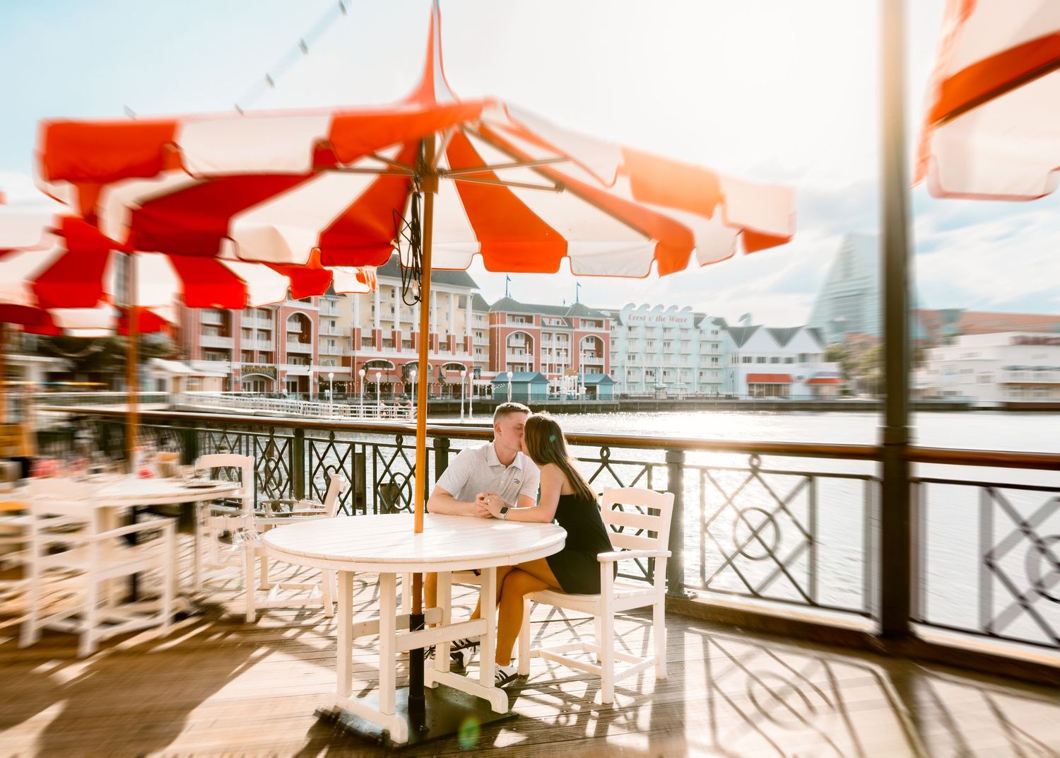 Young couple kissing at Disney Boardwalk during surprise proposal. Cred: LexTakePix