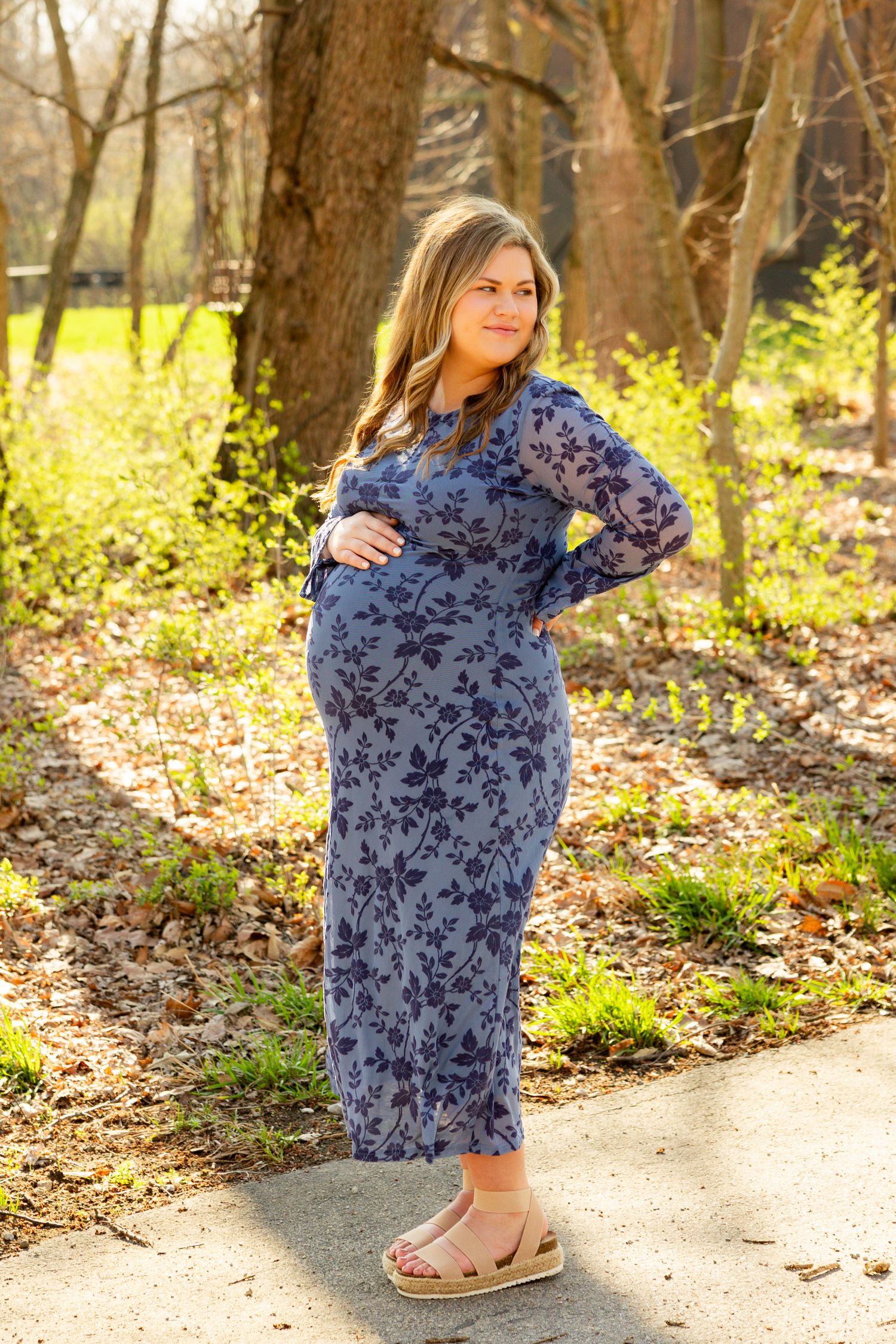 A floral print navy dress is shown in multiple angles on a woodland path with fallen leaves and natural lighting.