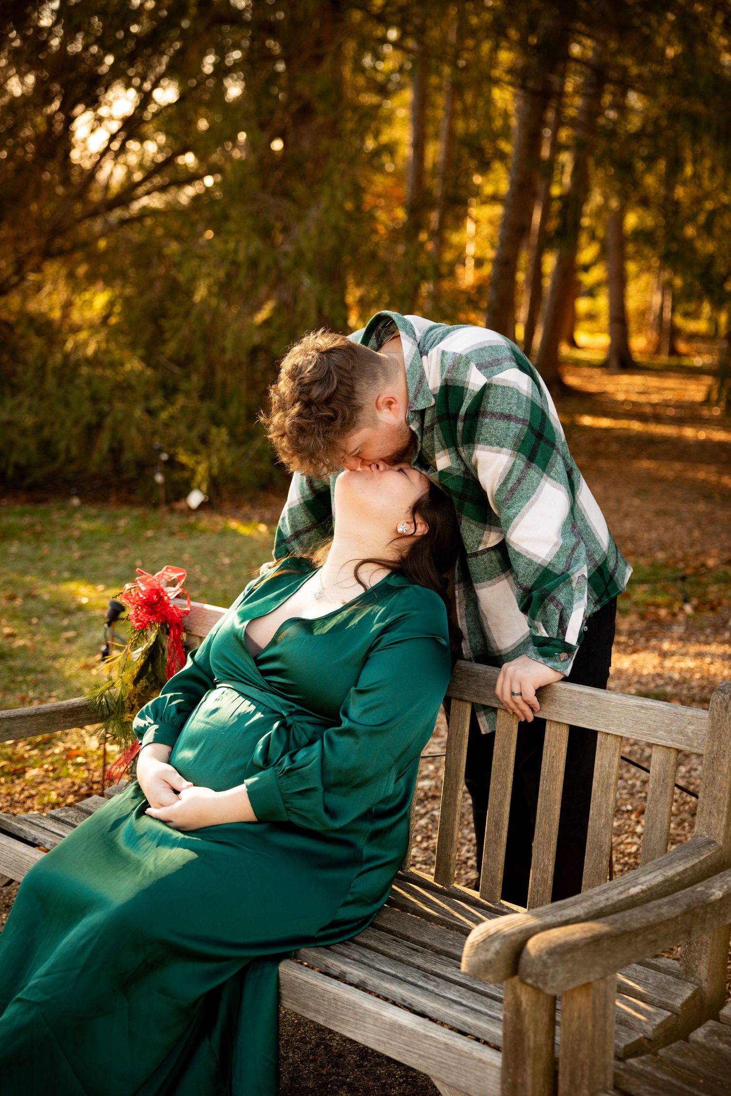 A romantic autumn scene with a couple sharing a tender moment on a wooden bench in a park with golden sunlit trees.