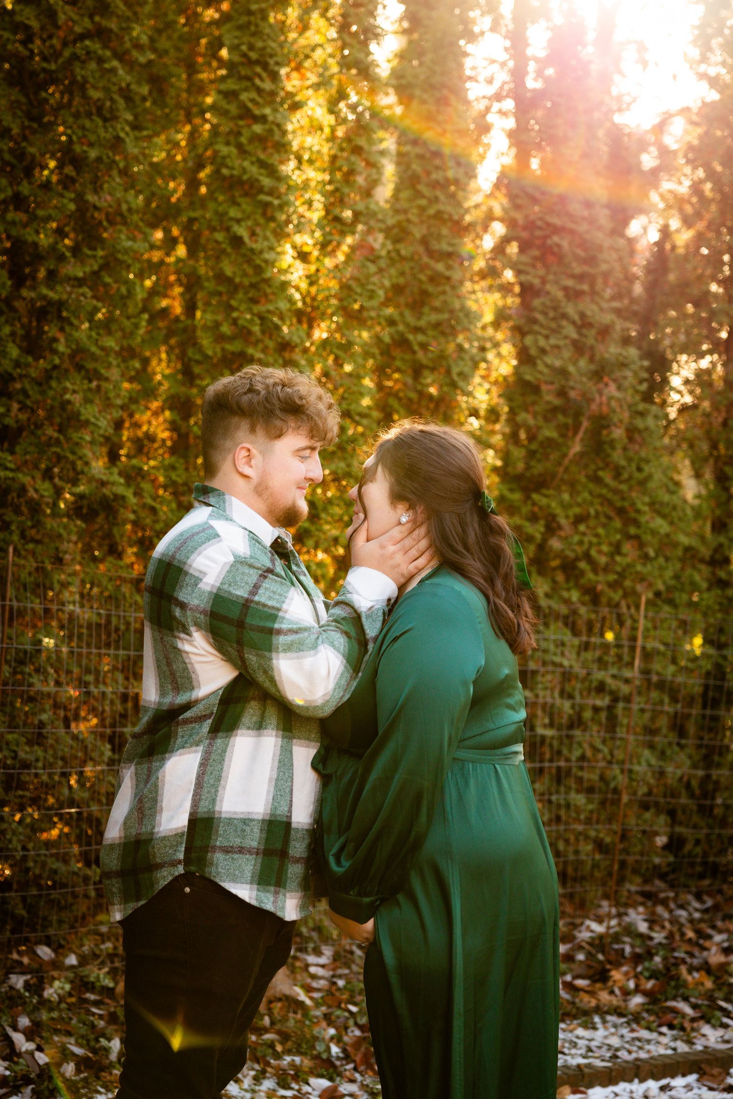 Romantic couple embraces tenderly in a garden with golden sunlight filtering through autumn foliage.