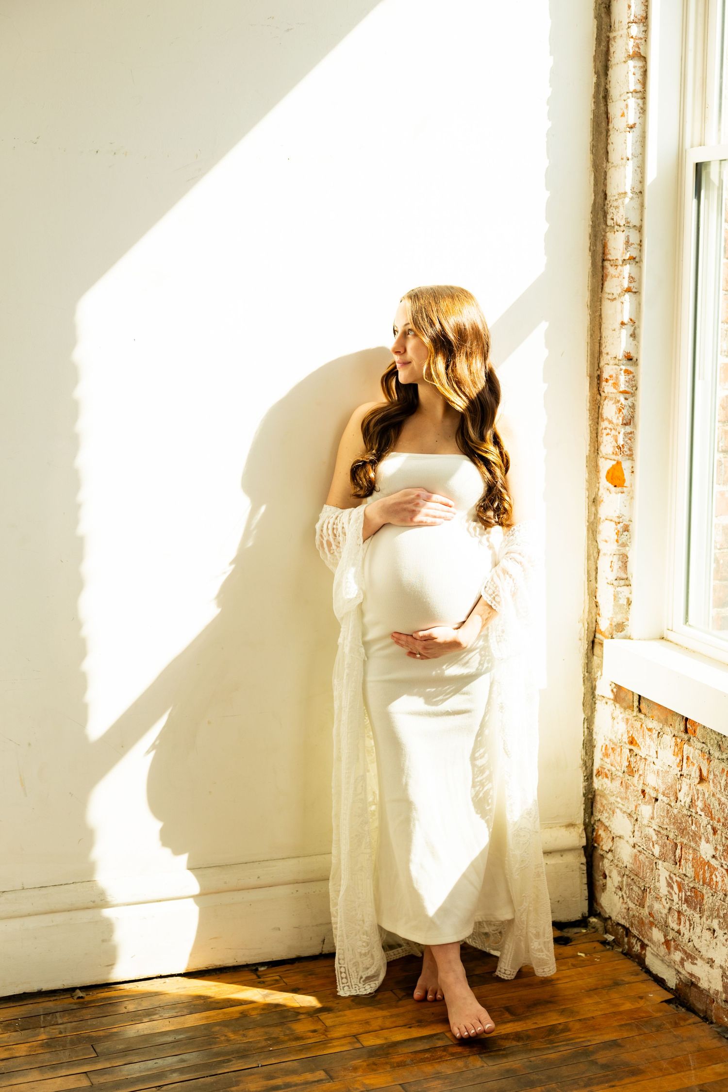 A series of connected images showing someone in a white dress sitting against a sunlit wall with exposed brick details.