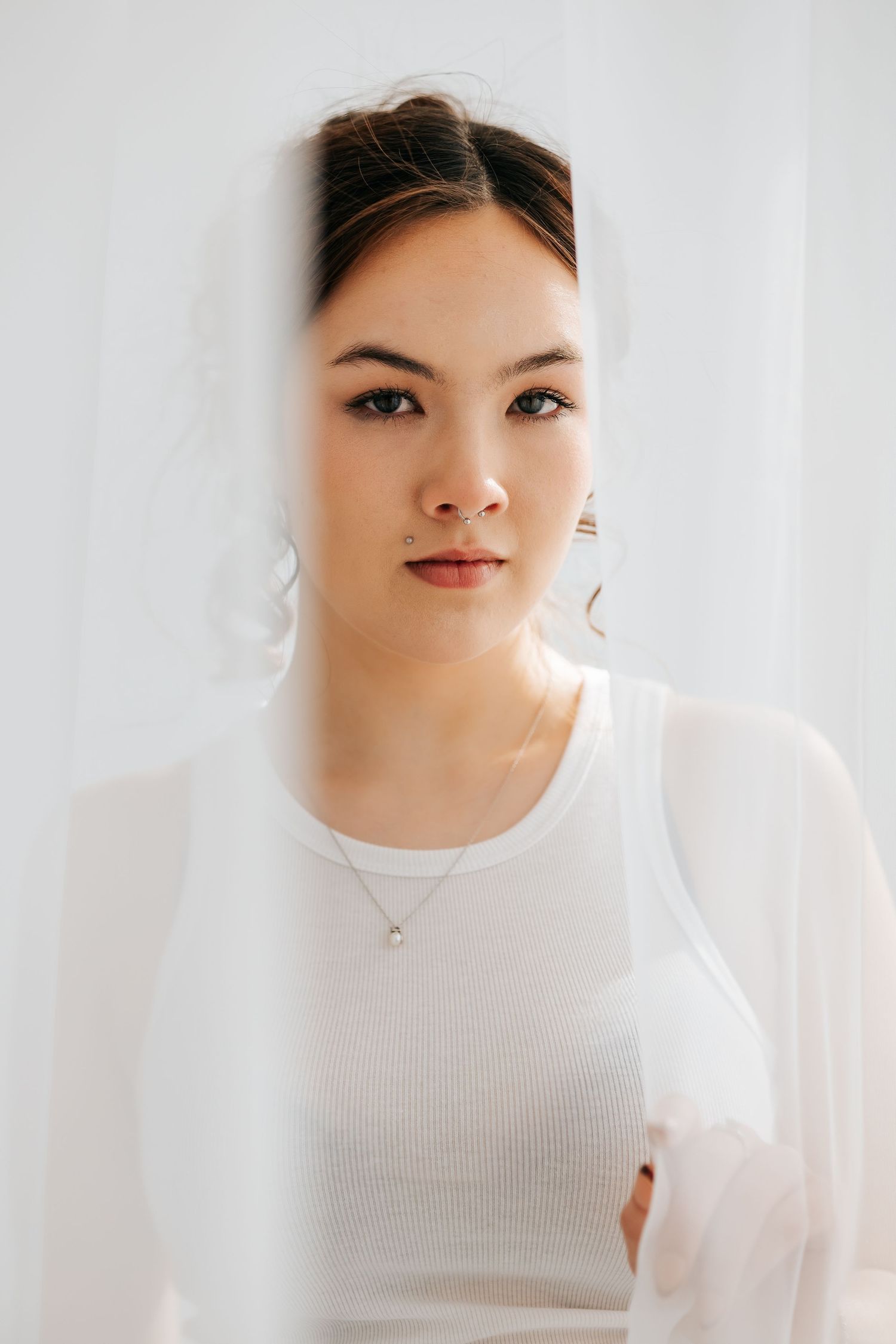 Portrait of person in white ribbed top against light background.