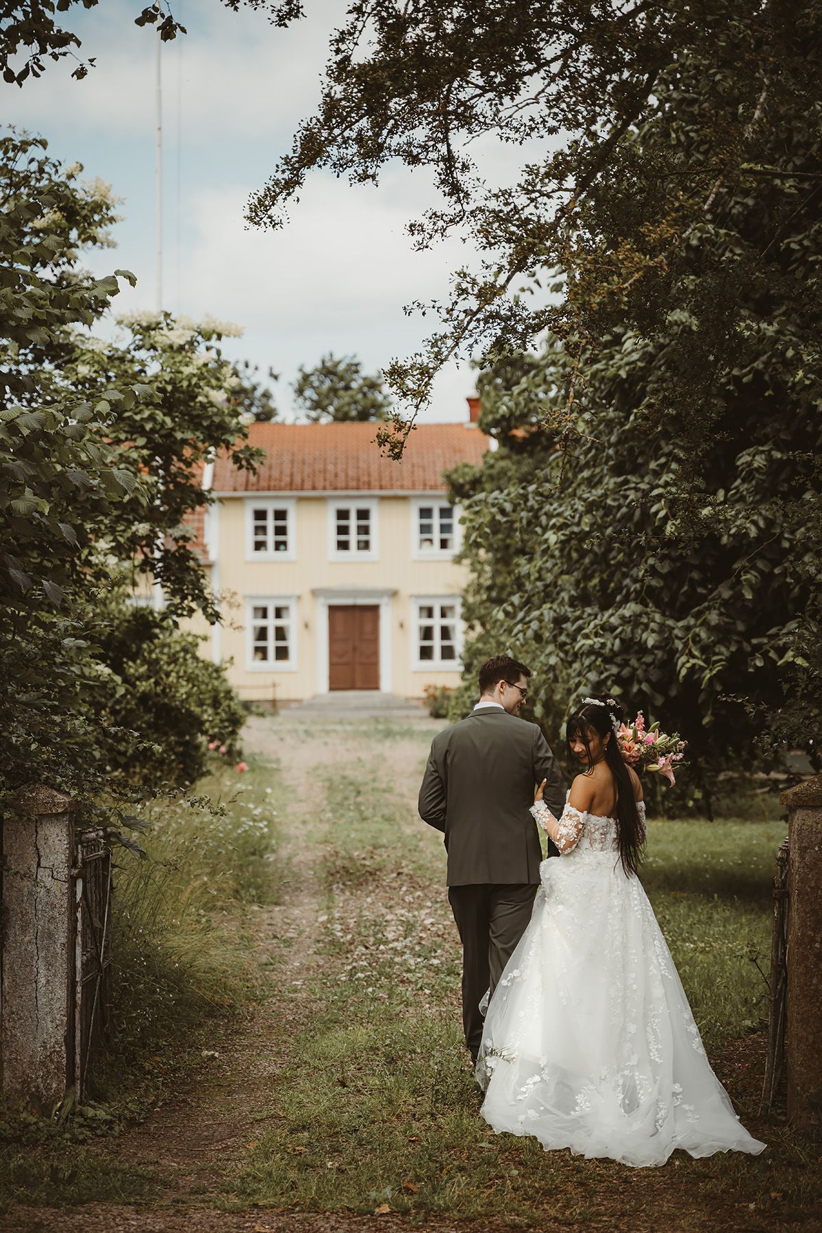 Brudpar står framför en vacker gul gammal herrgård på landet, bröllopsfoto fotograf Josefin Landhagen i Vadstena, Östergötland.