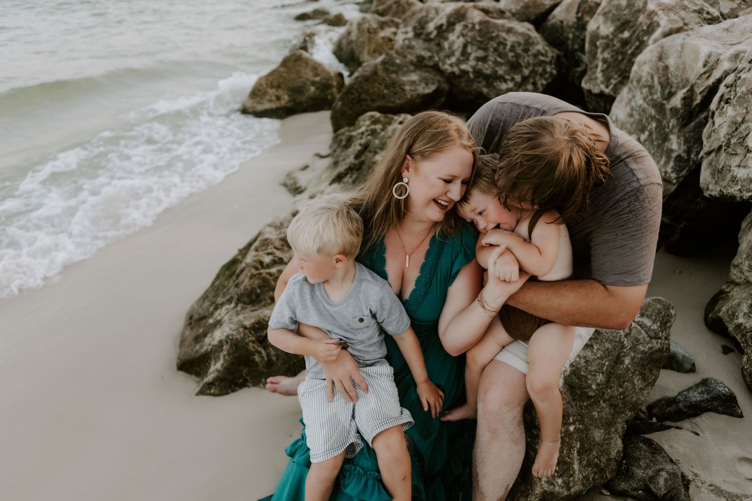 Family photo of a family laughing and kissing on the beach in Pensacola, Florida