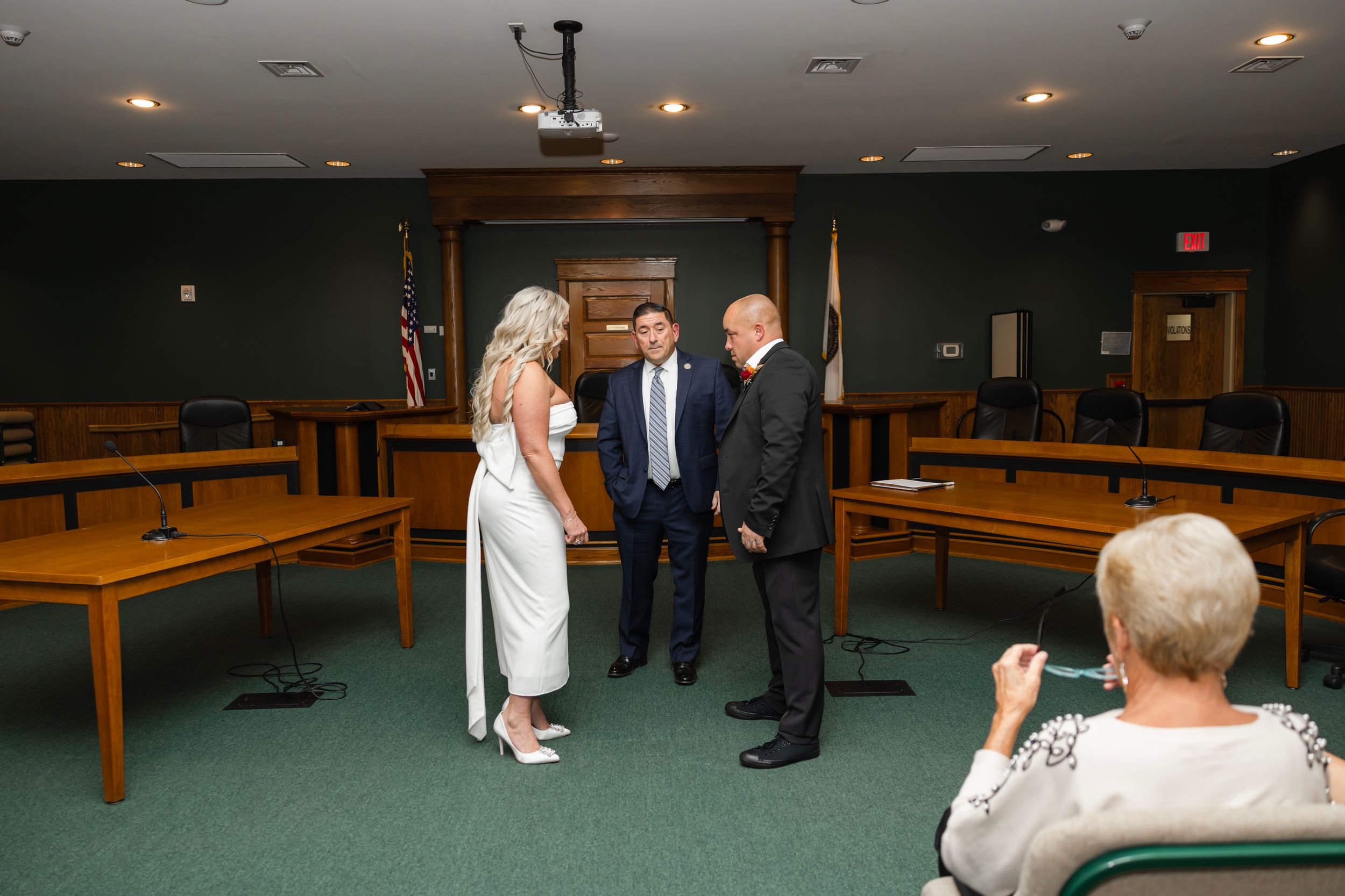People walking through a dimly lit bowling alley with recessed lighting overhead and wooden lanes visible. Northern NJ wedding photographer