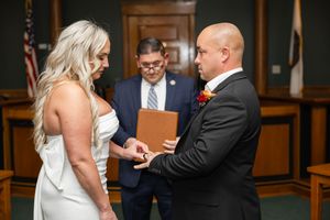 A couple exchanges rings during an intimate courthouse wedding ceremony with an officiant presiding over the moment. Northern NJ wedding pho