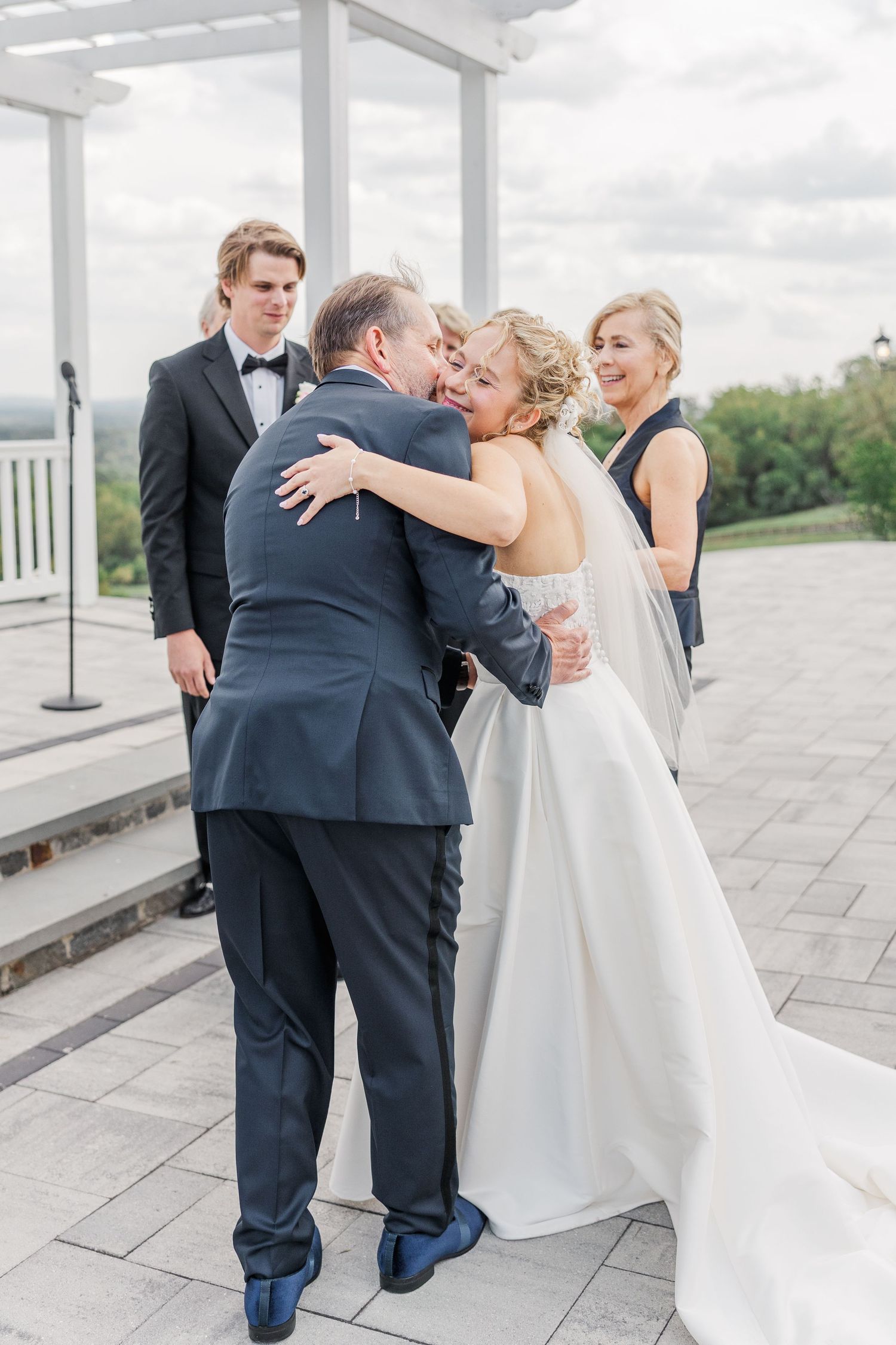 Emotional wedding moments captured on outdoor terrace with white columns.