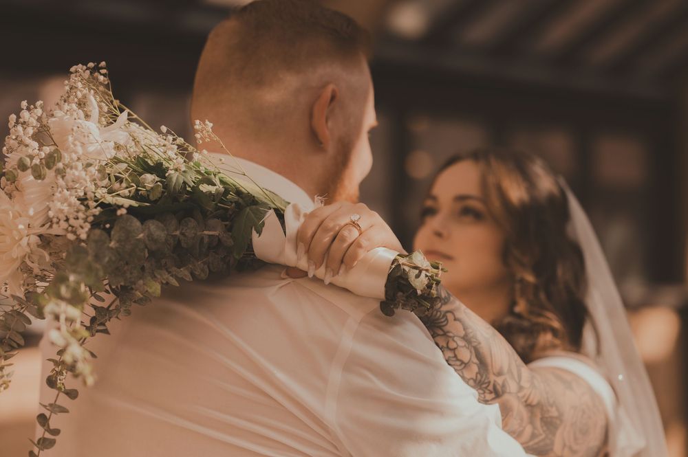 A romantic wedding couple embraces while standing on a stone bridge during their outdoor photo session.