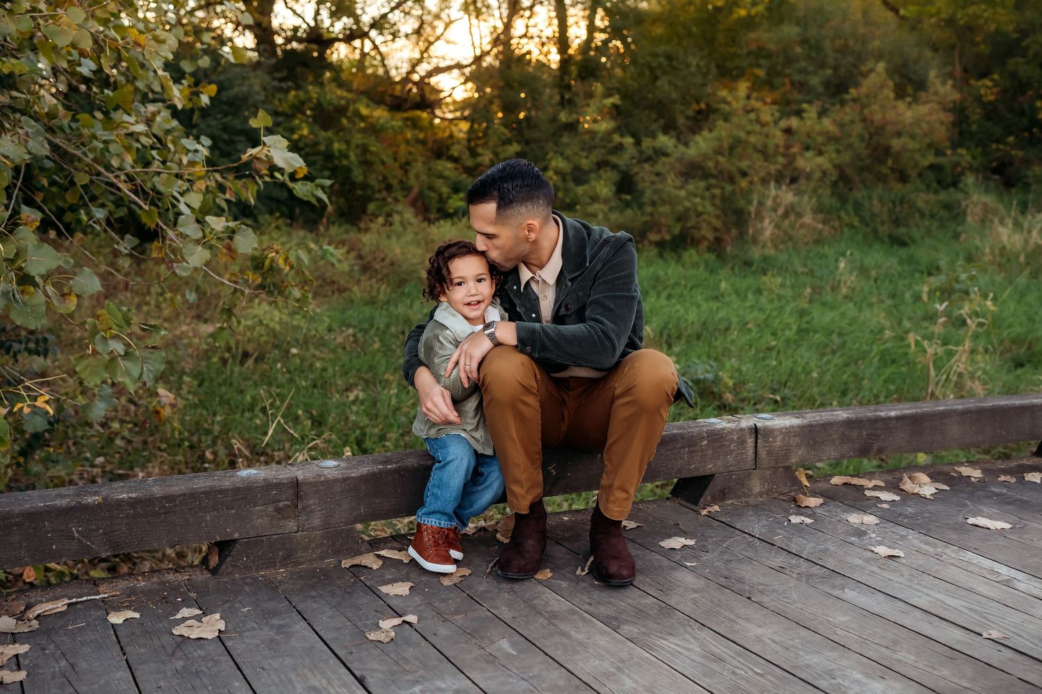 Family enjoying a tender moment together on a wooden deck during golden hour sunset in an autumn setting.