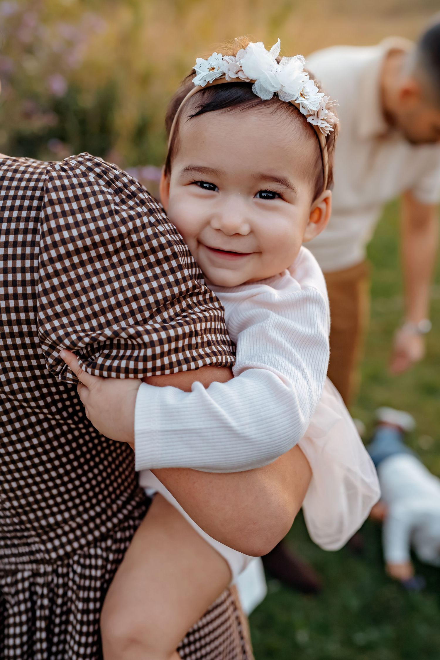 A series of candid photos showing tender embraces between parent and baby in a garden setting.