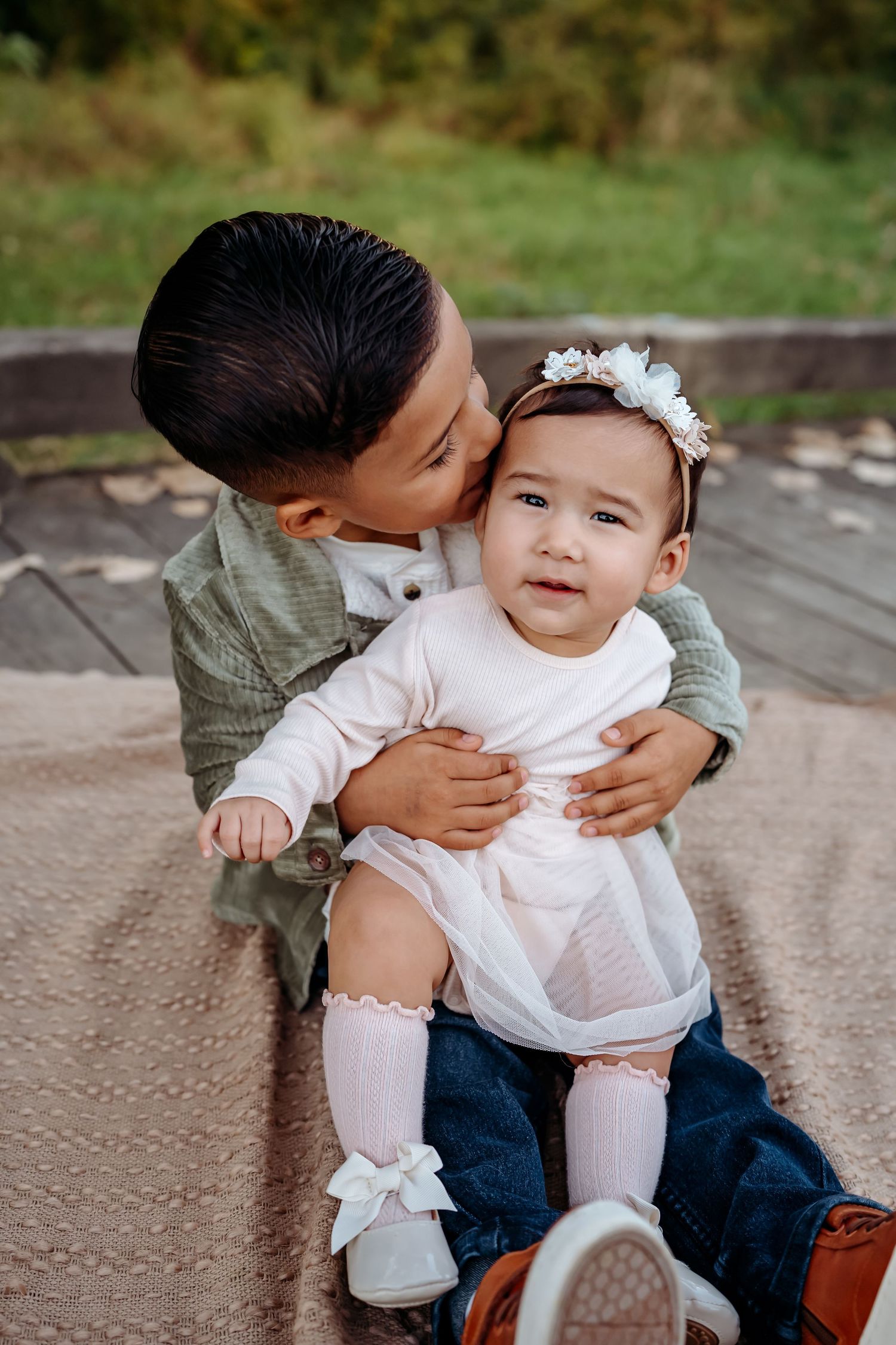 Sweet candid moments captured between siblings sitting together on outdoor steps in coordinating outfits.