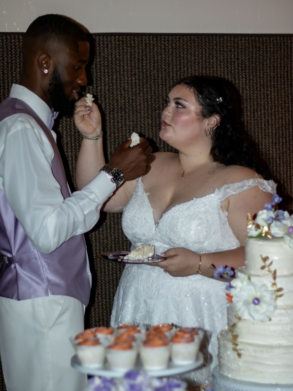 Bride and groom feeding each other wedding cake.